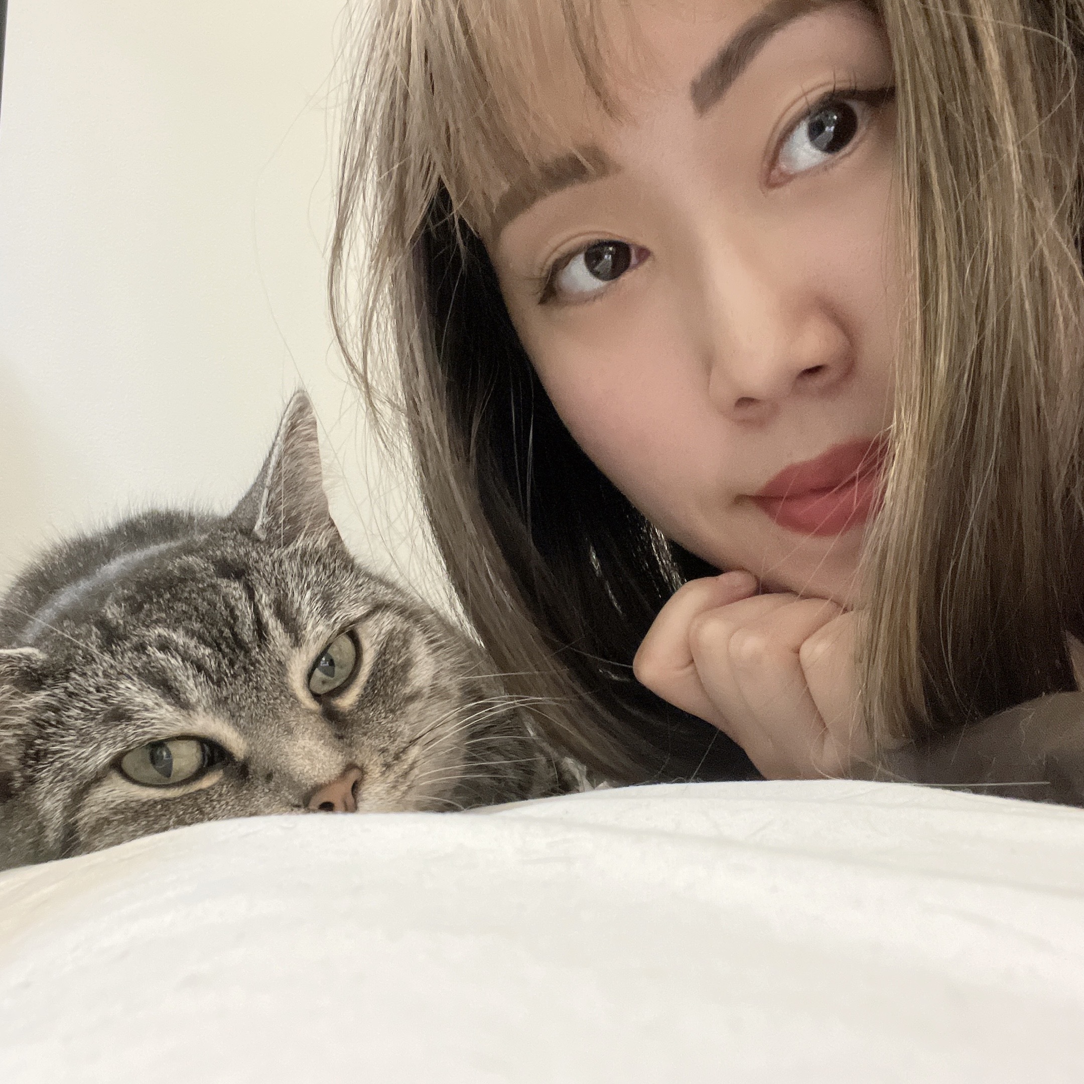 person smiling with a cat beside them